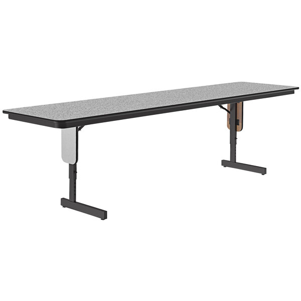 A rectangular table with a grey surface and panel legs.