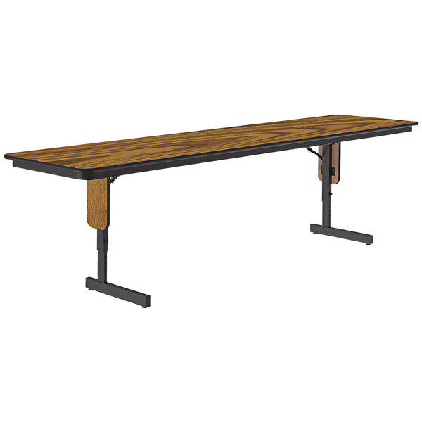 A rectangular table with a medium oak top and black panel legs.