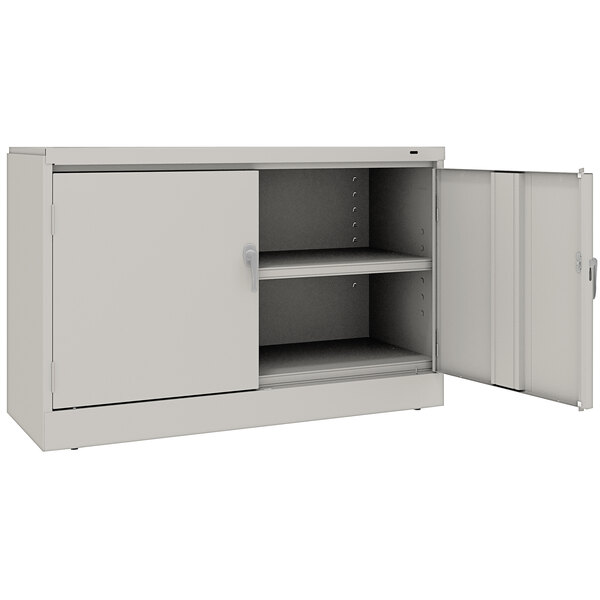 A light gray Tennsco storage cabinet with open doors.