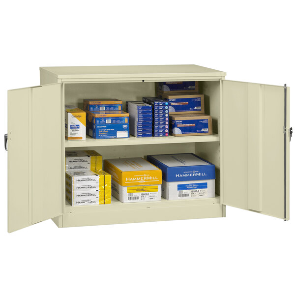 A Tennsco putty storage cabinet with solid doors and many boxes inside.