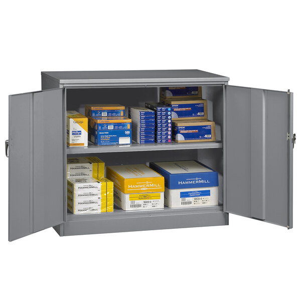 A dark gray Tennsco jumbo storage cabinet with solid doors filled with boxes and papers.