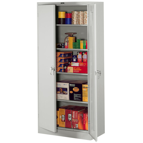 A Tennsco light gray metal storage cabinet with shelves full of products.