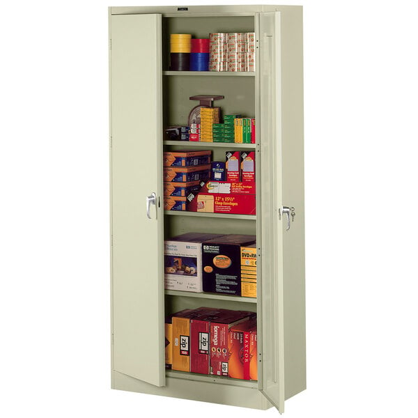 A Tennsco putty metal storage cabinet with shelves holding various items.