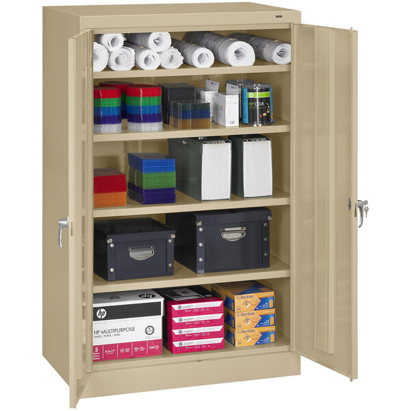 A sand Tennsco standard storage cabinet with solid doors and various items inside.