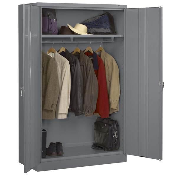 A gray metal Tennsco jumbo wardrobe cabinet with clothes and bags.