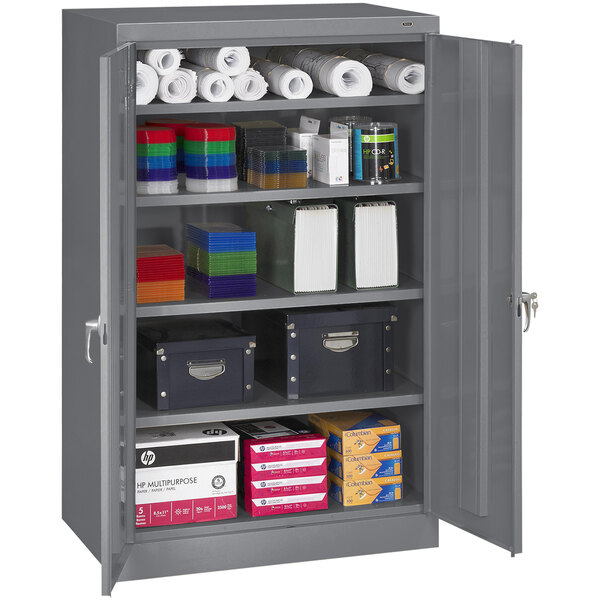 A dark gray Tennsco storage cabinet with solid doors filled with various items.