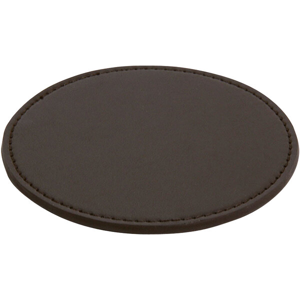 A round brown vinyl coaster with stitching on a table.