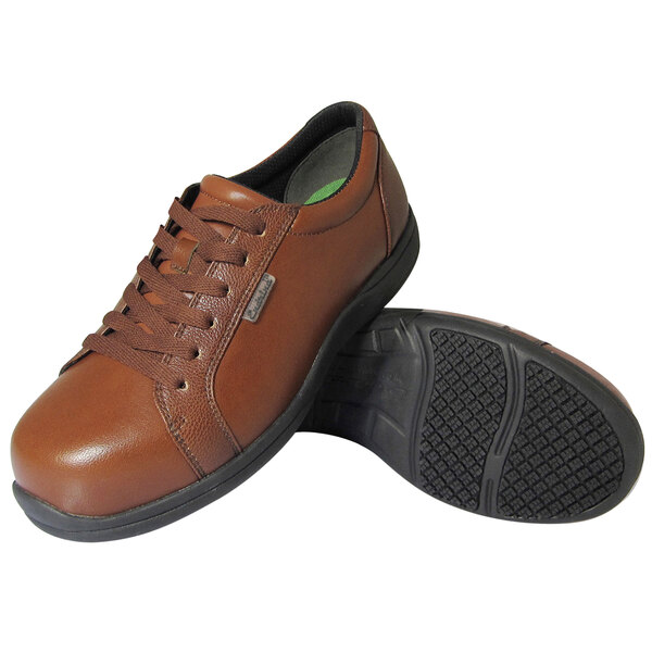 A pair of Genuine Grip brown leather non-slip oxford shoes with a black sole.