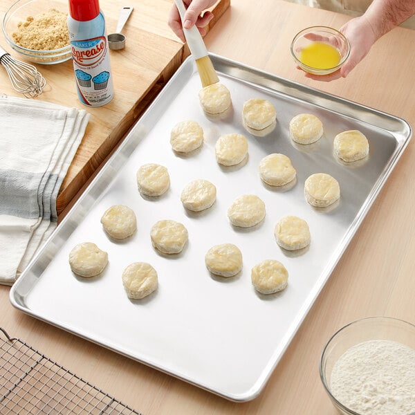 A person using a Baker's Mark aluminum sheet pan to make cookies.