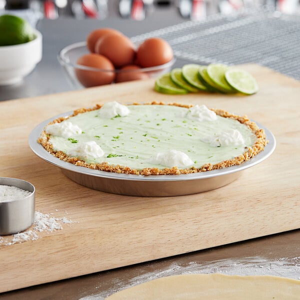 A pie with lime and whipped cream on a cutting board.