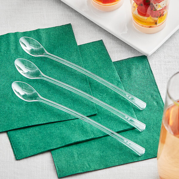 A group of clear plastic Visions tasting spoons on green napkins.