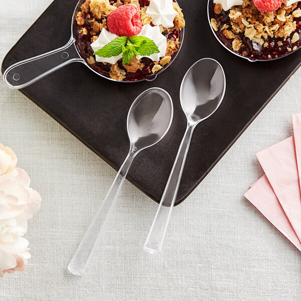 Two Visions clear plastic tasting spoons with dessert in small bowls.