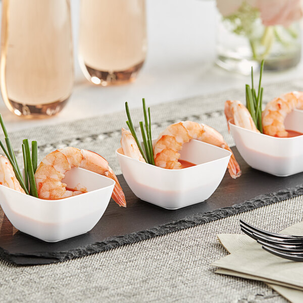 A group of Choice white square plastic mini bowls filled with shrimp and green onions on a black tray.