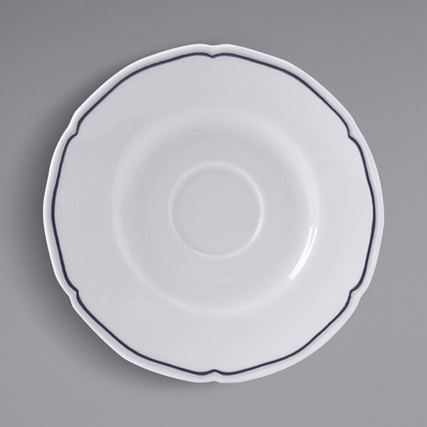 A white Tuxton saucer with a scalloped edge and blue trim.