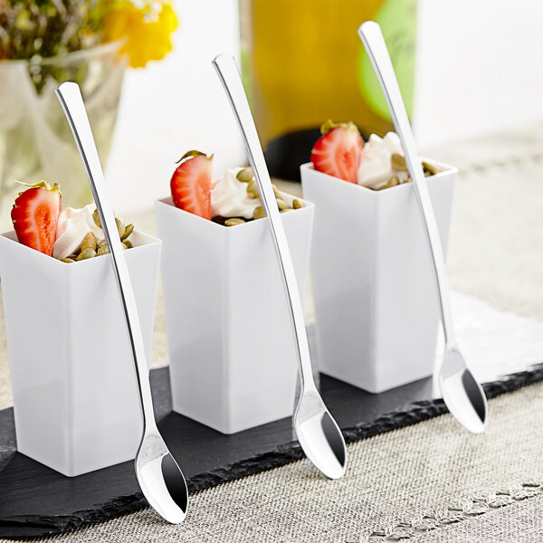 A close-up of a white container with strawberries and a Visions silver plastic tasting spoon.