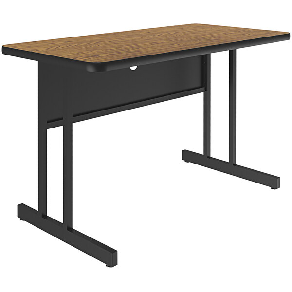 A Correll medium oak desk with black legs.