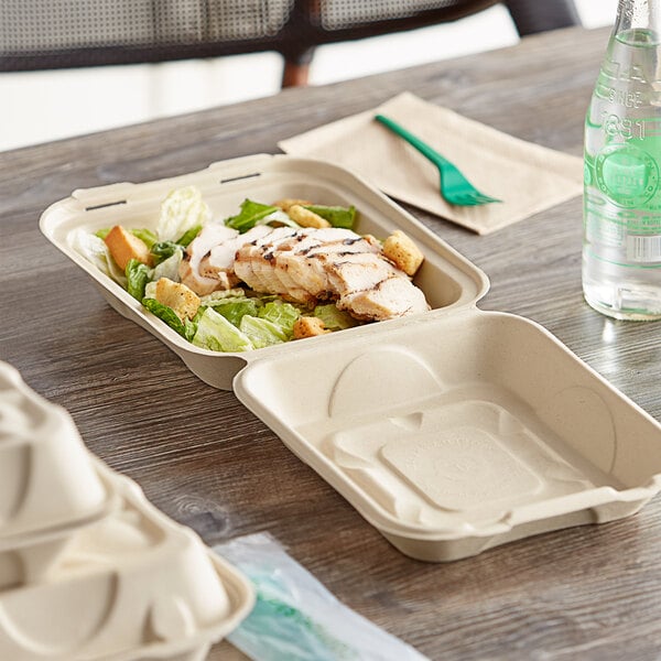 World Centric compostable clamshell containers holding salad and chicken on a table.