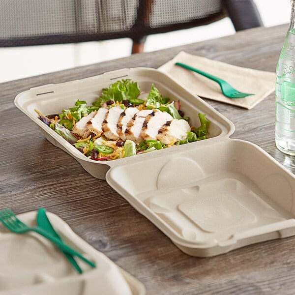 A salad in a World Centric compostable clamshell container on a table with a green fork.