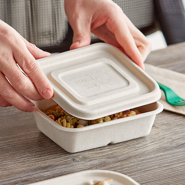 A person holding a World Centric compostable container of food.