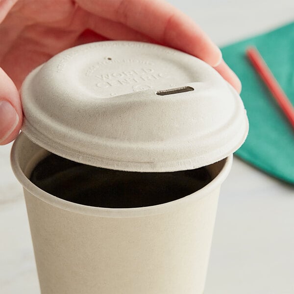 A hand using a World Centric fiber hot cup sip lid on a coffee cup.