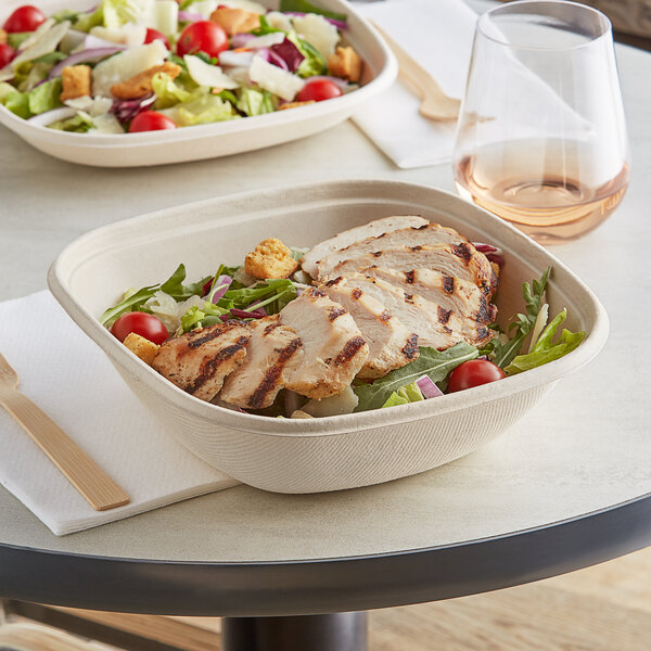 A salad with grilled chicken and tomatoes in a World Centric compostable square fiber bowl.