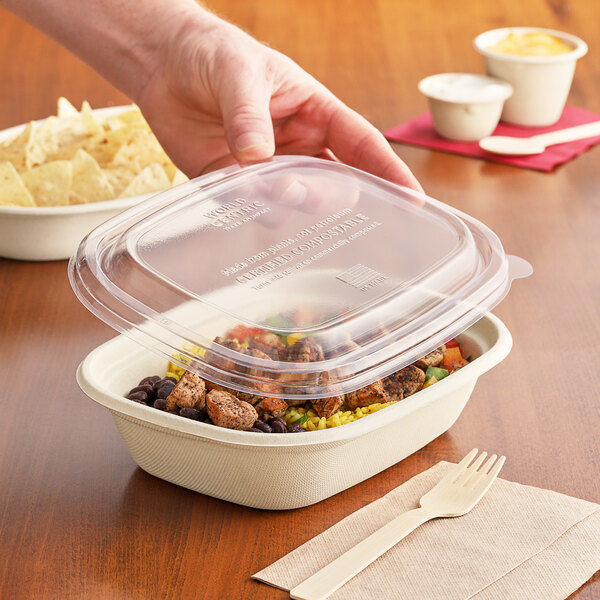 A hand places a World Centric clear plastic lid on a bowl of food.