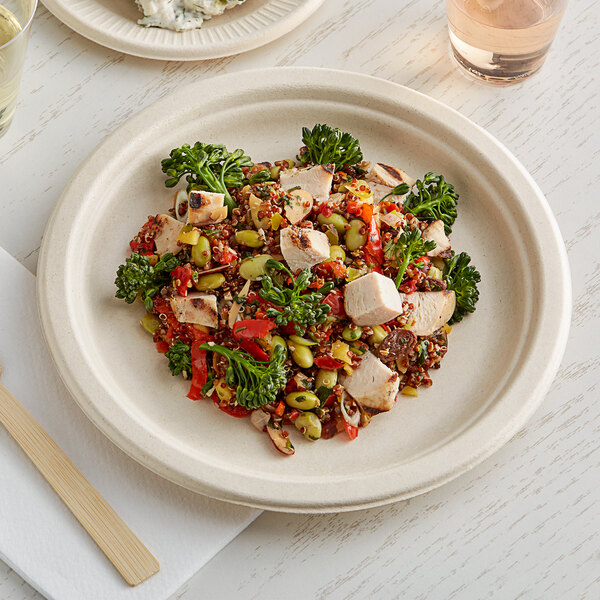 A World Centric compostable fiber plate with food including vegetables on a table.