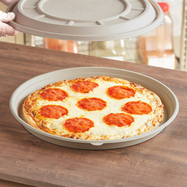 World Centric compostable fiber round pizza container base with a pizza in it.