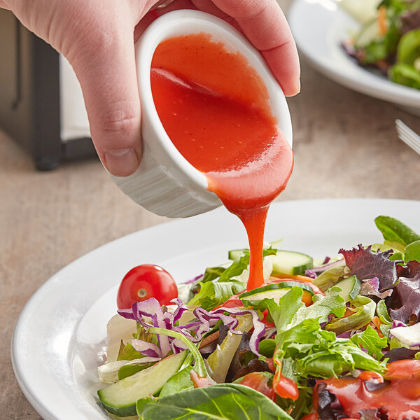A person pouring Kraft Catalina dressing over a salad.