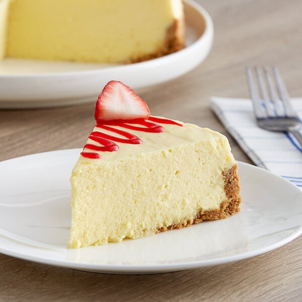 A slice of JELL-O cheesecake with a strawberry on a plate.