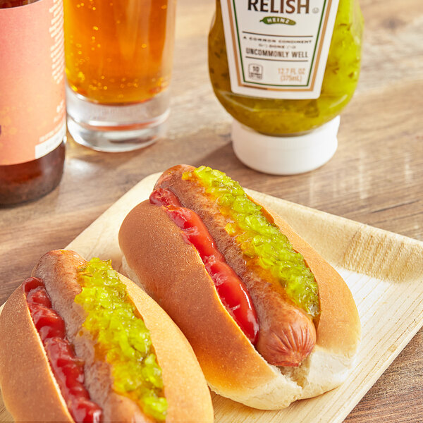 Two hot dogs with Heinz Sweet Relish on them on a plate.