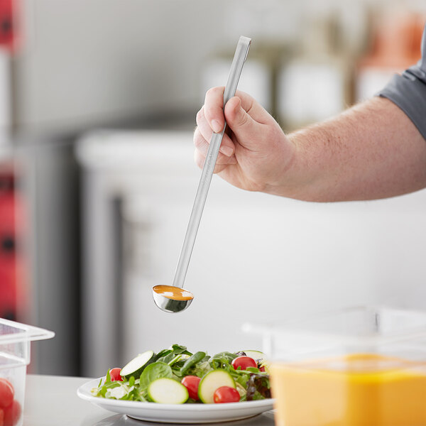 A person using a Choice stainless steel ladle to spoon salad onto a plate.