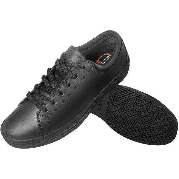 A close-up of a Genuine Grip black leather shoe with laces and an orange sole.
