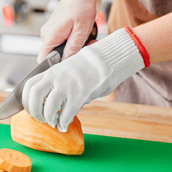 A person wearing Choice Level cut-resistant gloves cutting a piece of food.