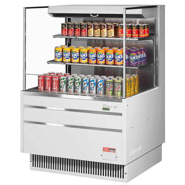 A white Turbo Air horizontal refrigerated curtain merchandiser with cans of soda inside.