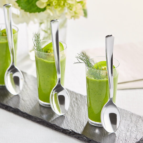 Three Visions silver plastic tasting spoons in glasses of green liquid on a tray.