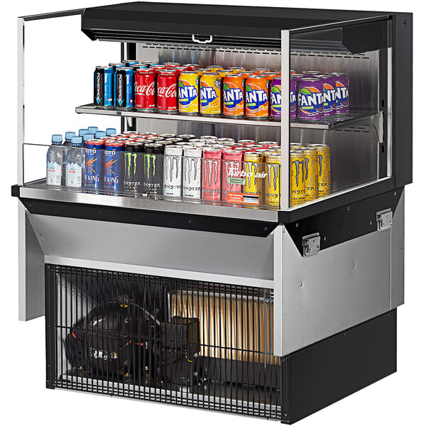 A Turbo Air drop-in refrigerated display case with cans of soda on a shelf.
