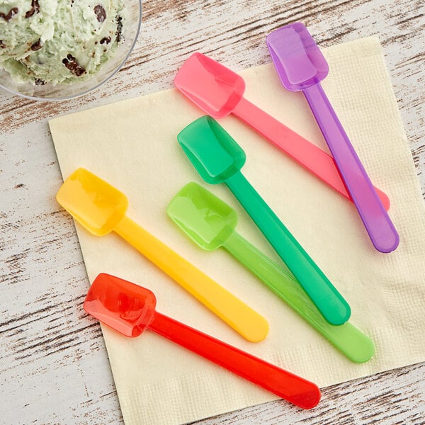 A group of Choice plastic gelato spoons in assorted colors on a napkin.