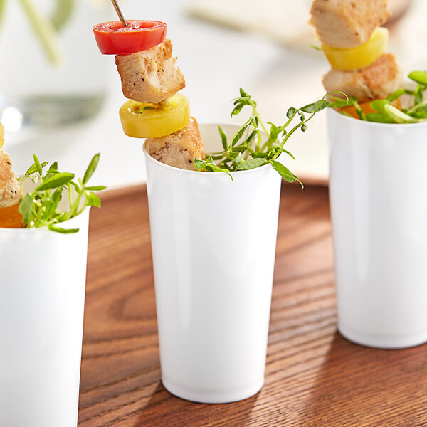 A close-up of three white Choice plastic cups filled with food.