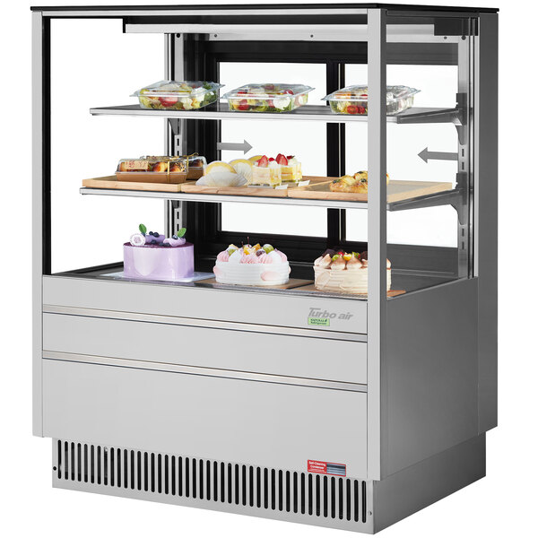 A Turbo Air refrigerated bakery display case with desserts on trays inside.