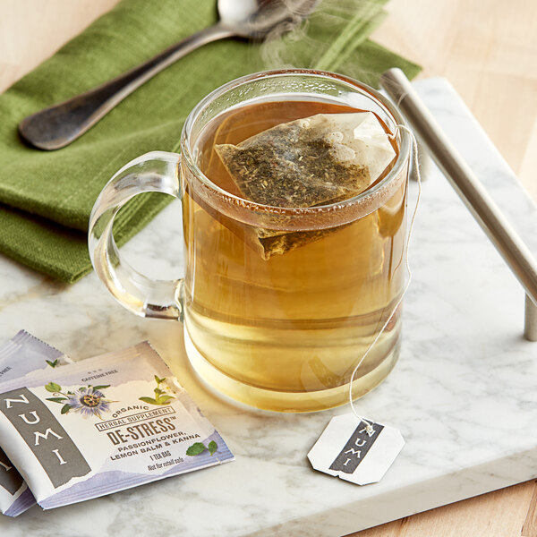 A glass mug of Numi Organic De-Stress Herbal Tea with a tea bag in it.