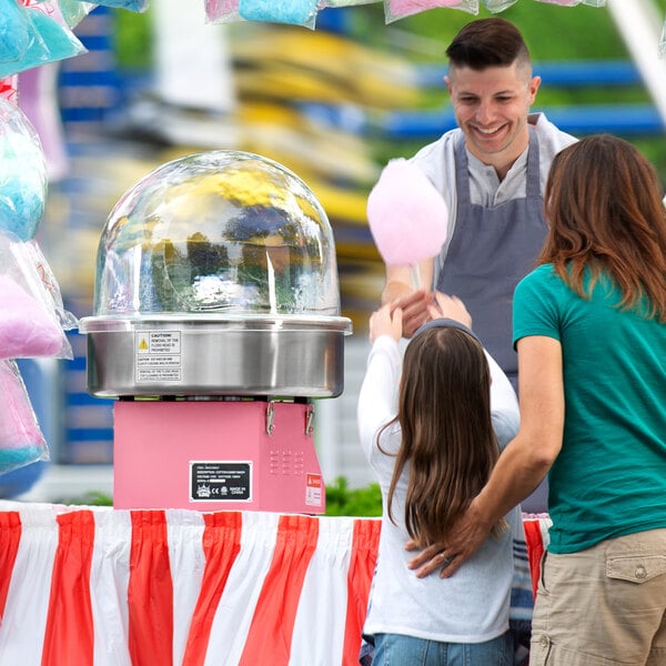A man giving a woman cotton candy made with a Carnival King cotton candy machine.
