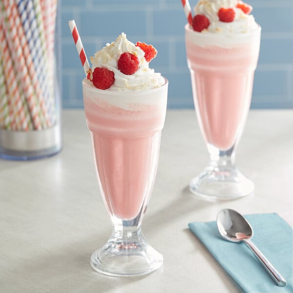Two glasses of Oringer raspberry milkshakes with straws and raspberries.