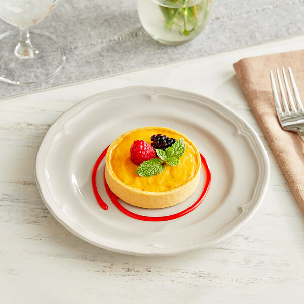 An Acopa Condesa warm gray porcelain dessert plate with food on it.