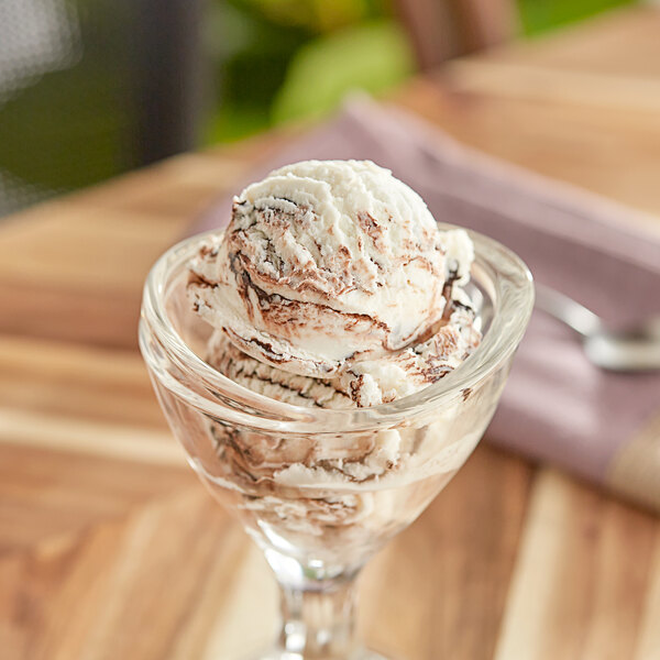 A glass cup with a scoop of Oringer chocolate variegate on top of ice cream.