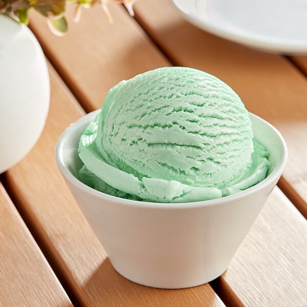 A scoop of green Oringer mint chocolate chip ice cream in a white bowl.