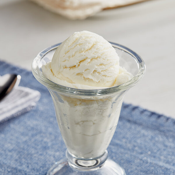 A glass cup with a scoop of lemon ice cream.