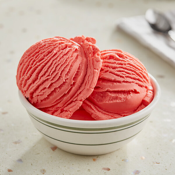 A bowl of pink ice cream made with Oringer Red Raspberry hard serve ice cream flavoring on a counter.
