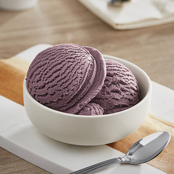 A bowl of Oringer black raspberry ice cream with a spoon on a table.