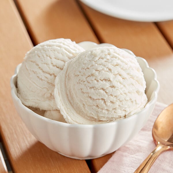 A bowl of white ice cream with a spoon on a table.